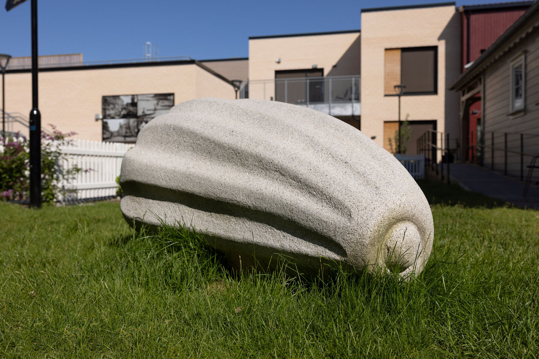 Skulptur av frø står på en gressplen. Foto.