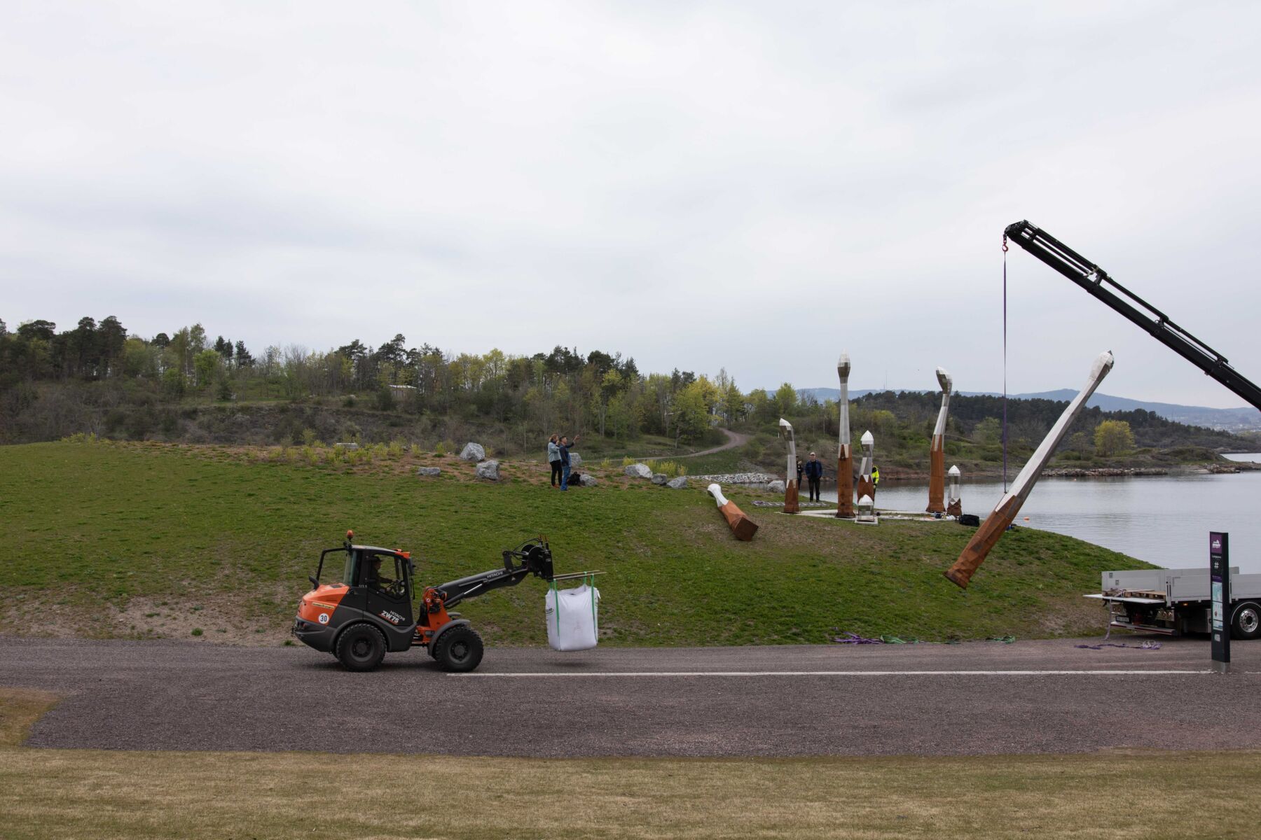 4 personer er i arbeid med å montere en skulpturgruppe på Langøyene. Foto