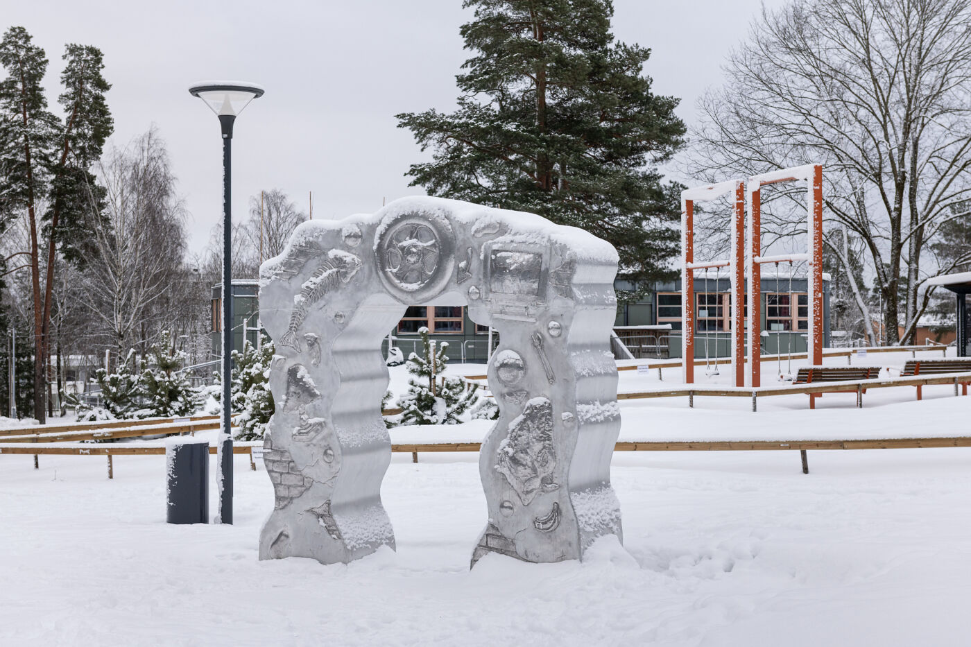 Foto av Morten Jensen Vågens skulptur Samfunnsportalen utendørs i en snødekt skolegård.