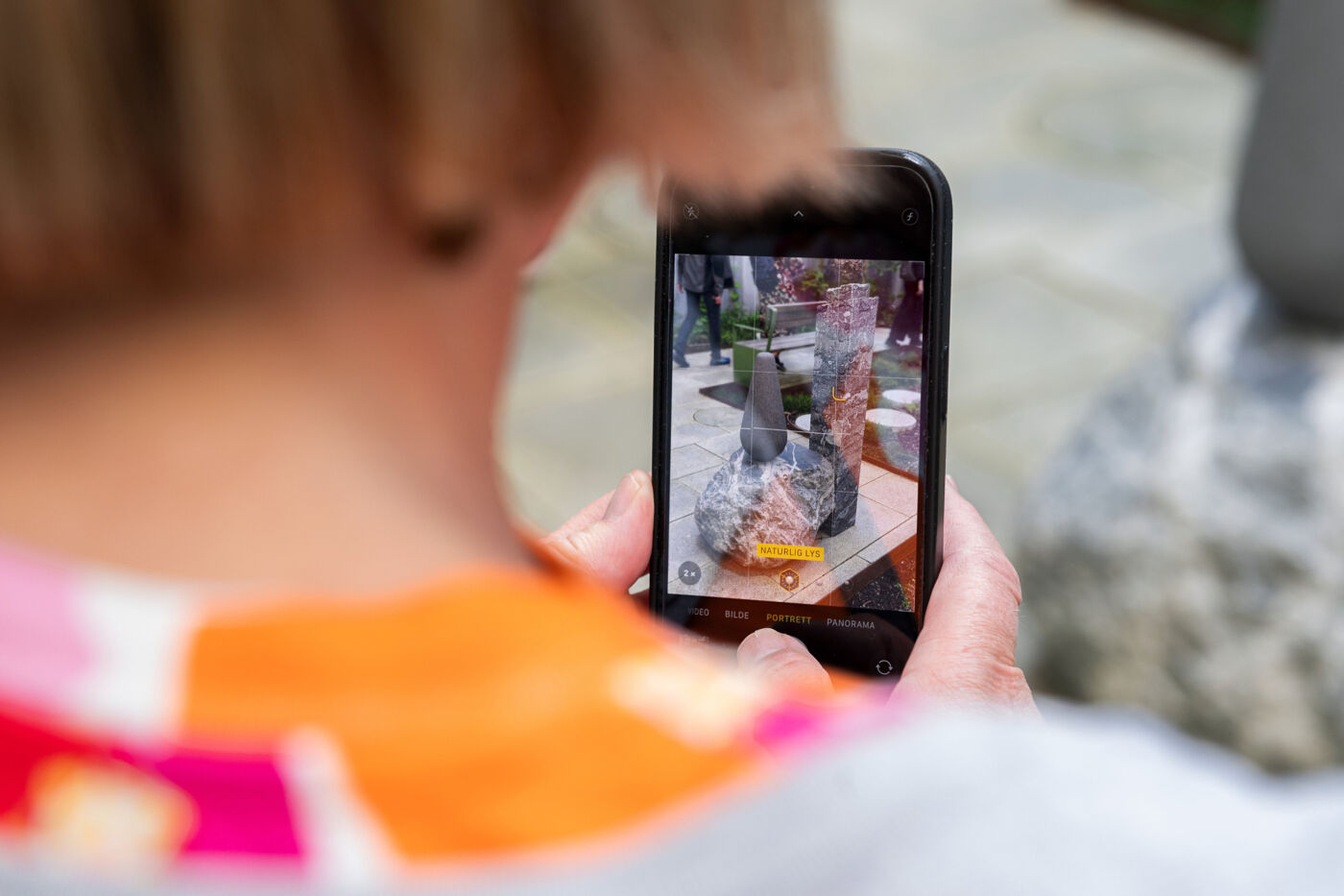 Foto av en person som fotograferer et kunstverk med mobilen sin.