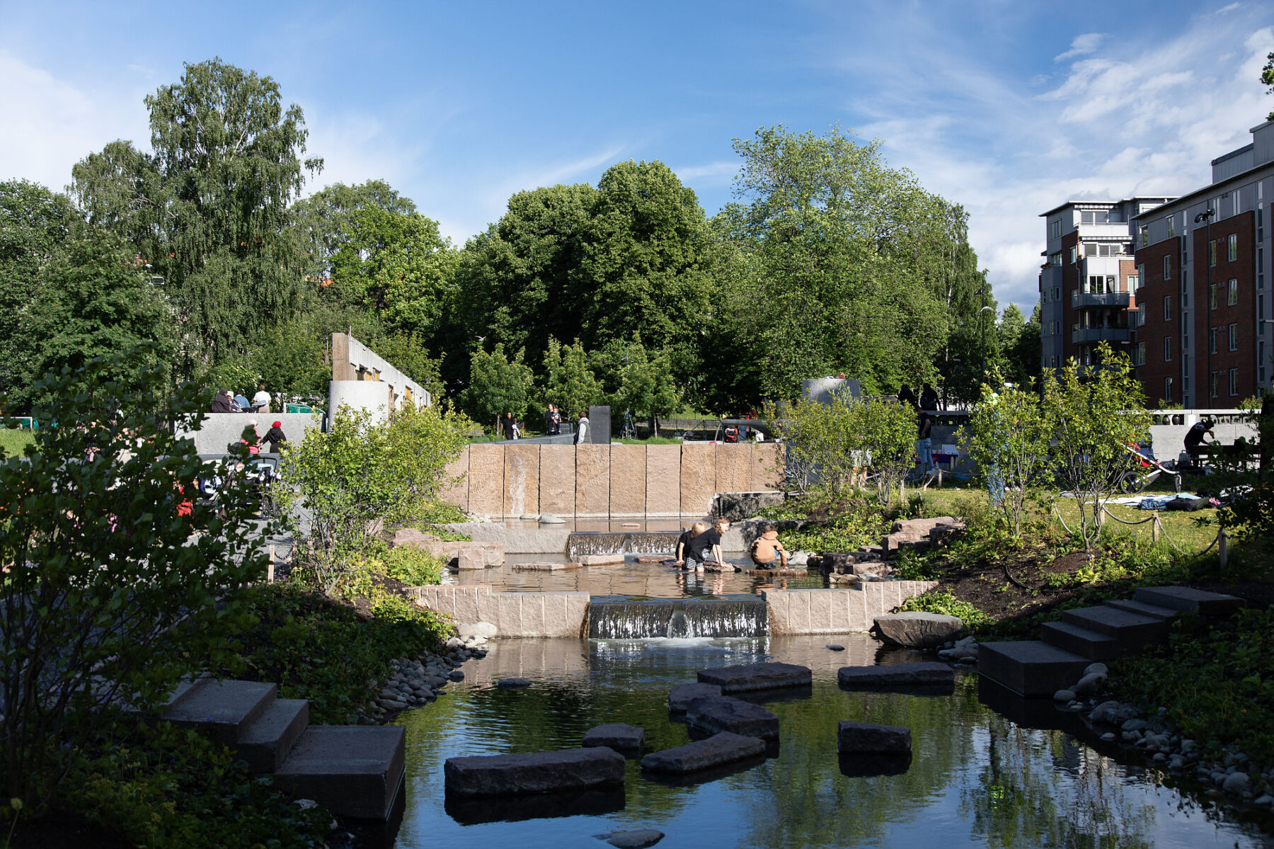 Foto av bekk, kunst og grøntområde i Klosterenga park.