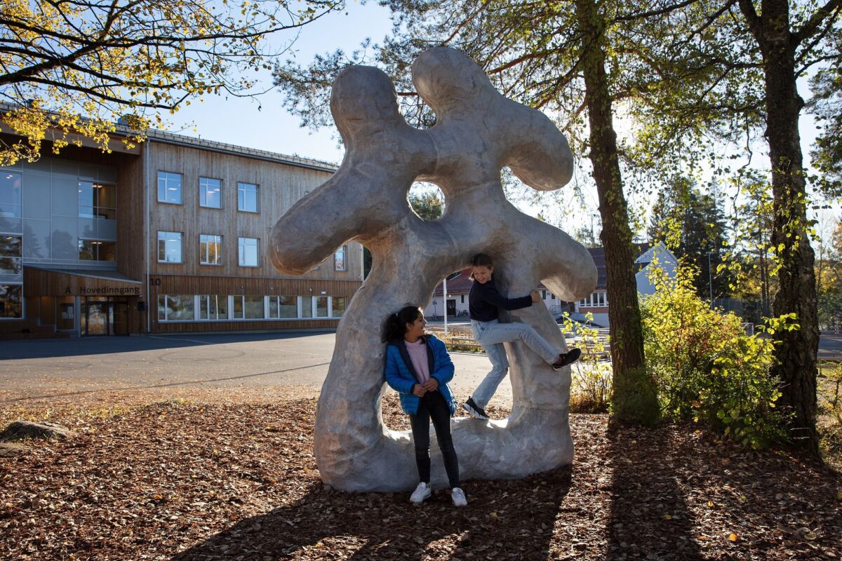 Foto av skulptur med organiske former ved Prinsdal skole. Barn leker i den.