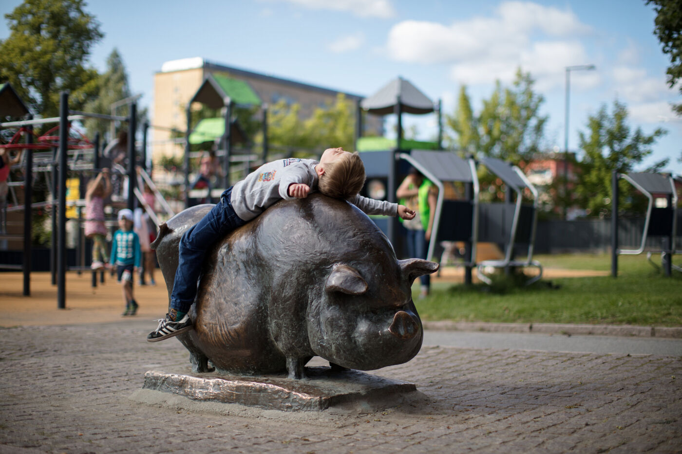 Foto av et barn liggende oppå en skulptur av et svin.