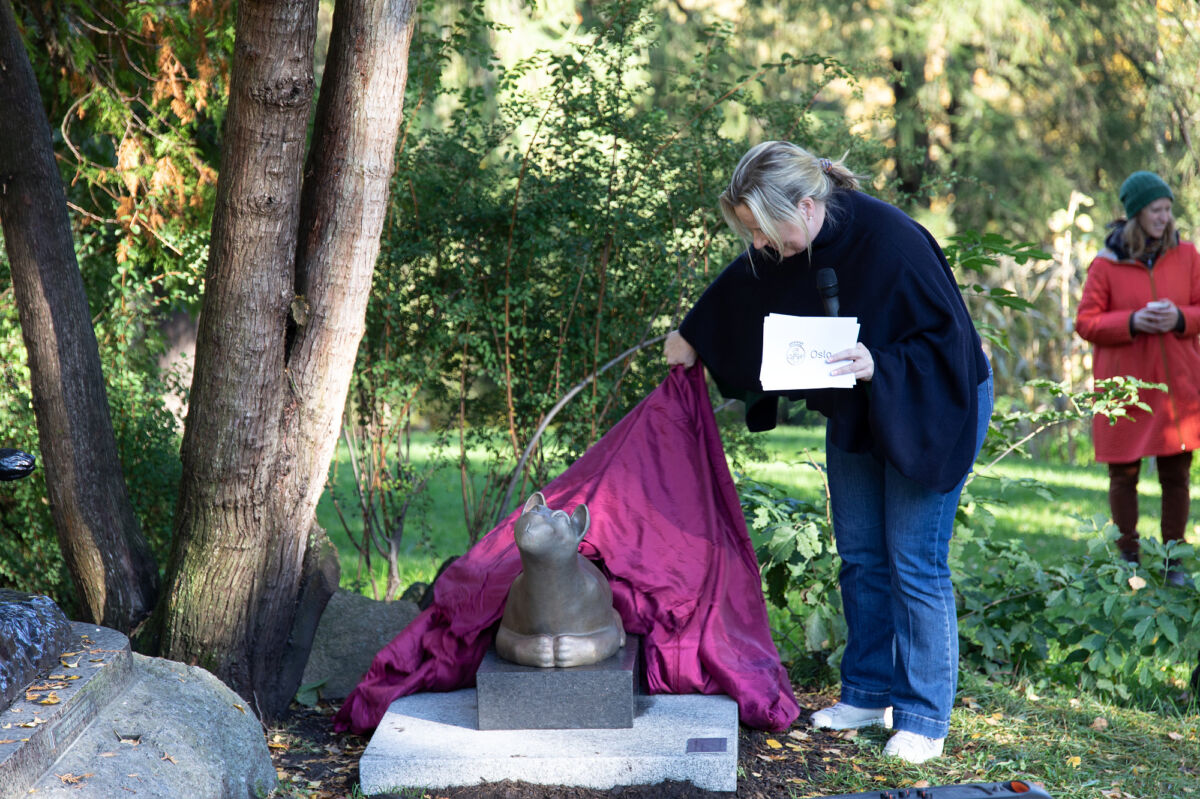 Foto av person som avduker en skulptur av en løveunge.