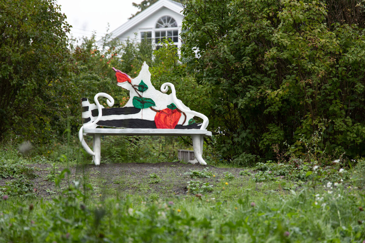 Foto av en skulpturbenk stående i en grønn hage.