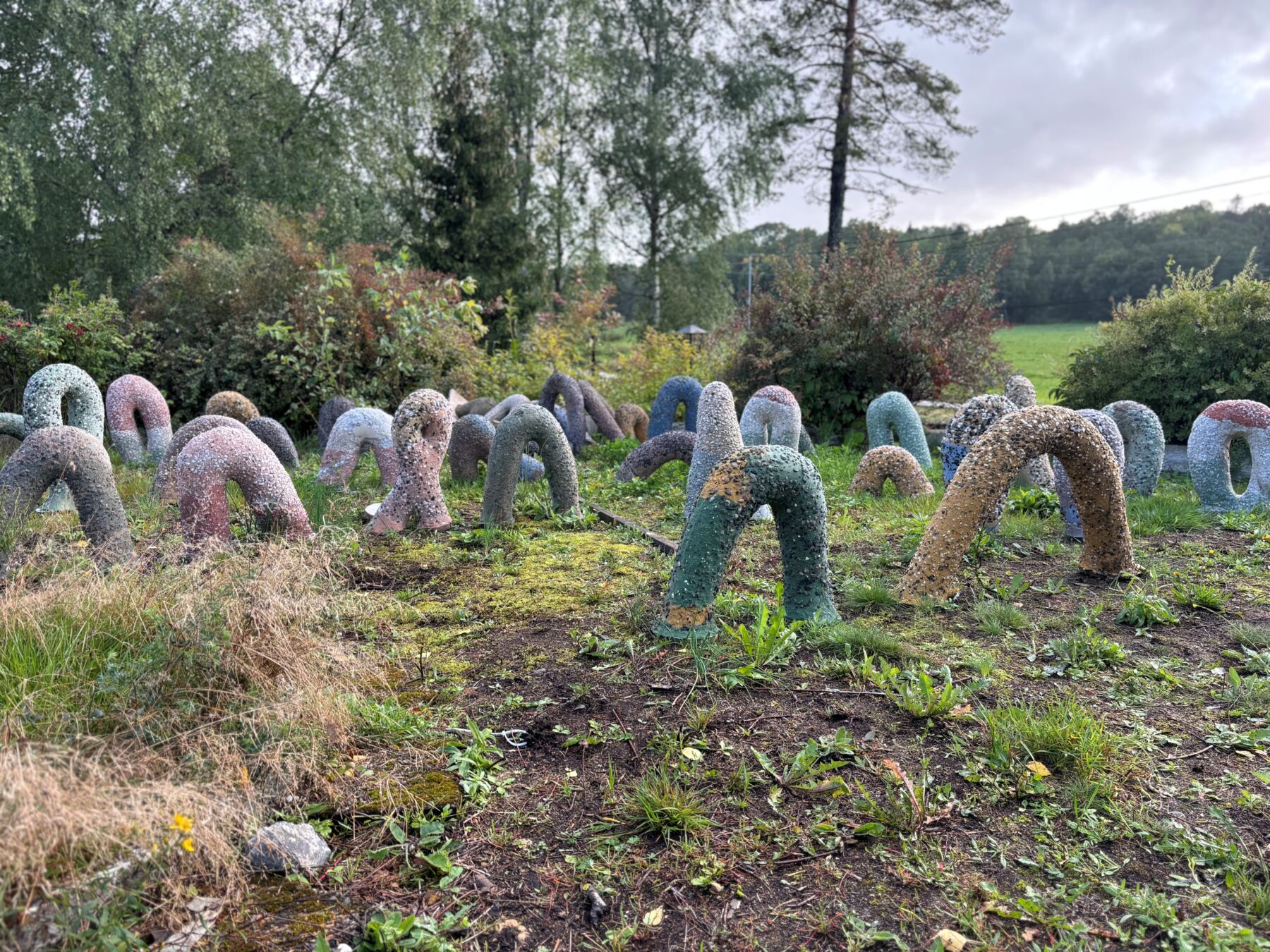 Foto av en skulptur bestående av mange sylinderformede buer i et landskap.